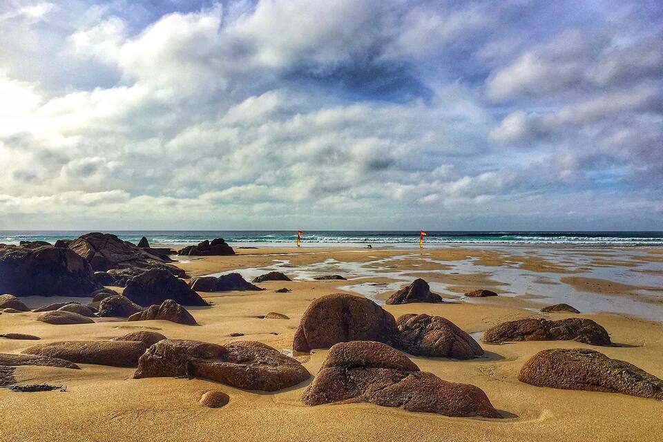 A rocky beach with large boulders and a cloudy sky.
