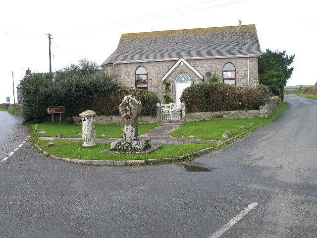 A stone building with a signboard, a roundabout, and a stone monument.