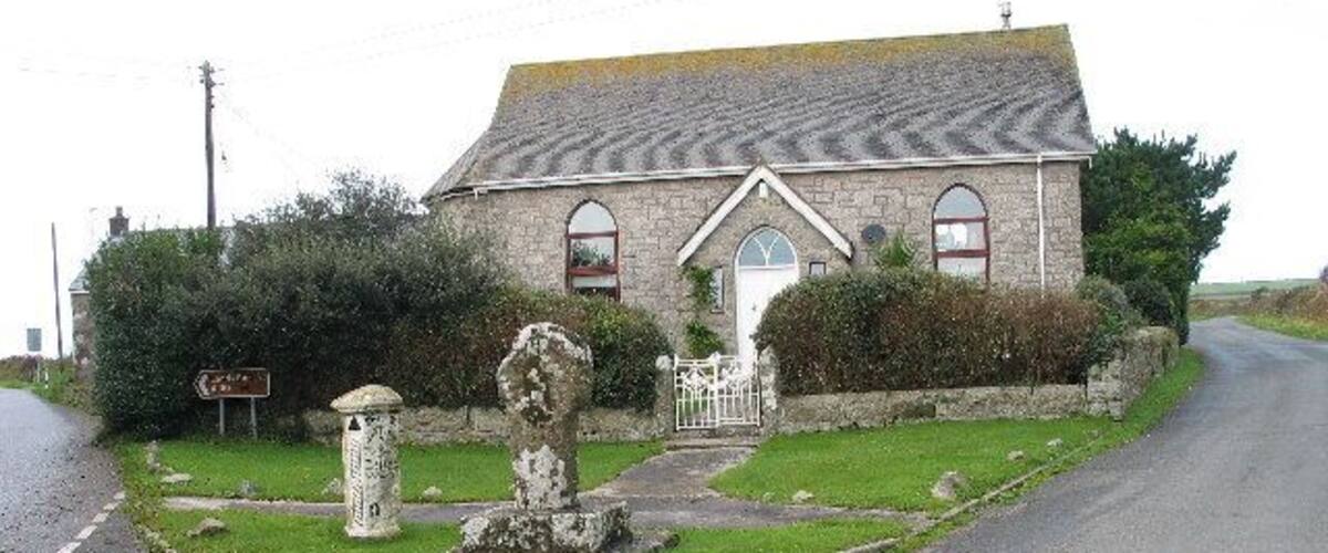 A stone building with a signboard, a roundabout, and a stone monument.