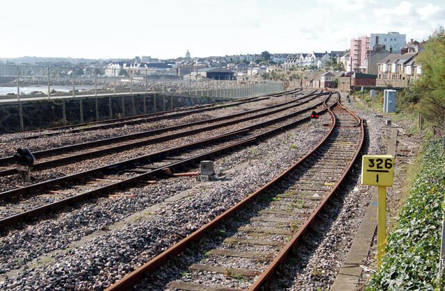 Railway tracks, a sign with the number 326, and a coastal town in the background.