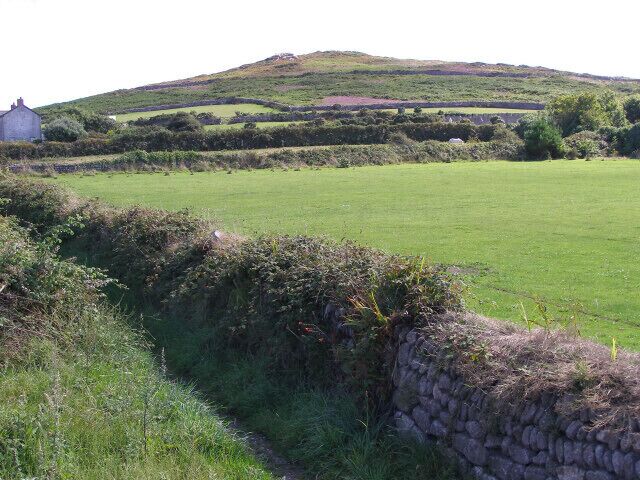 View towards Carn Eanes from Pendeen car park. Carn Eanes looms over Higher Boscaswell. The field in the foreground is Pendeen School's sports pitch.
