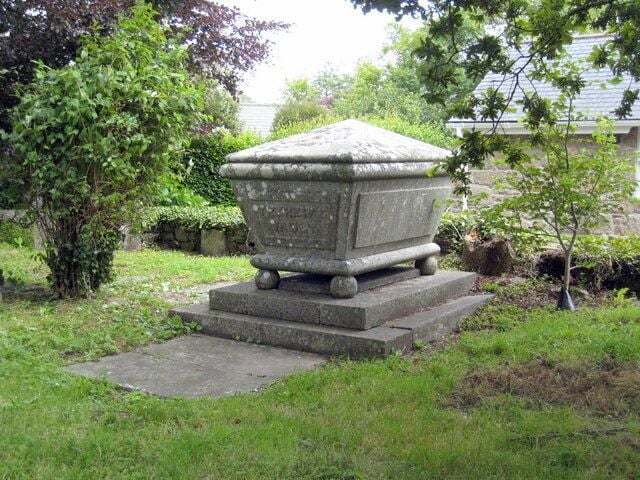 A stone urn on a pedestal in a garden.