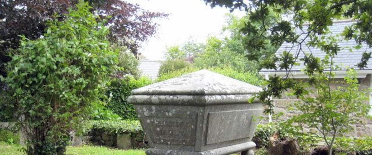 A stone urn on a pedestal in a garden.