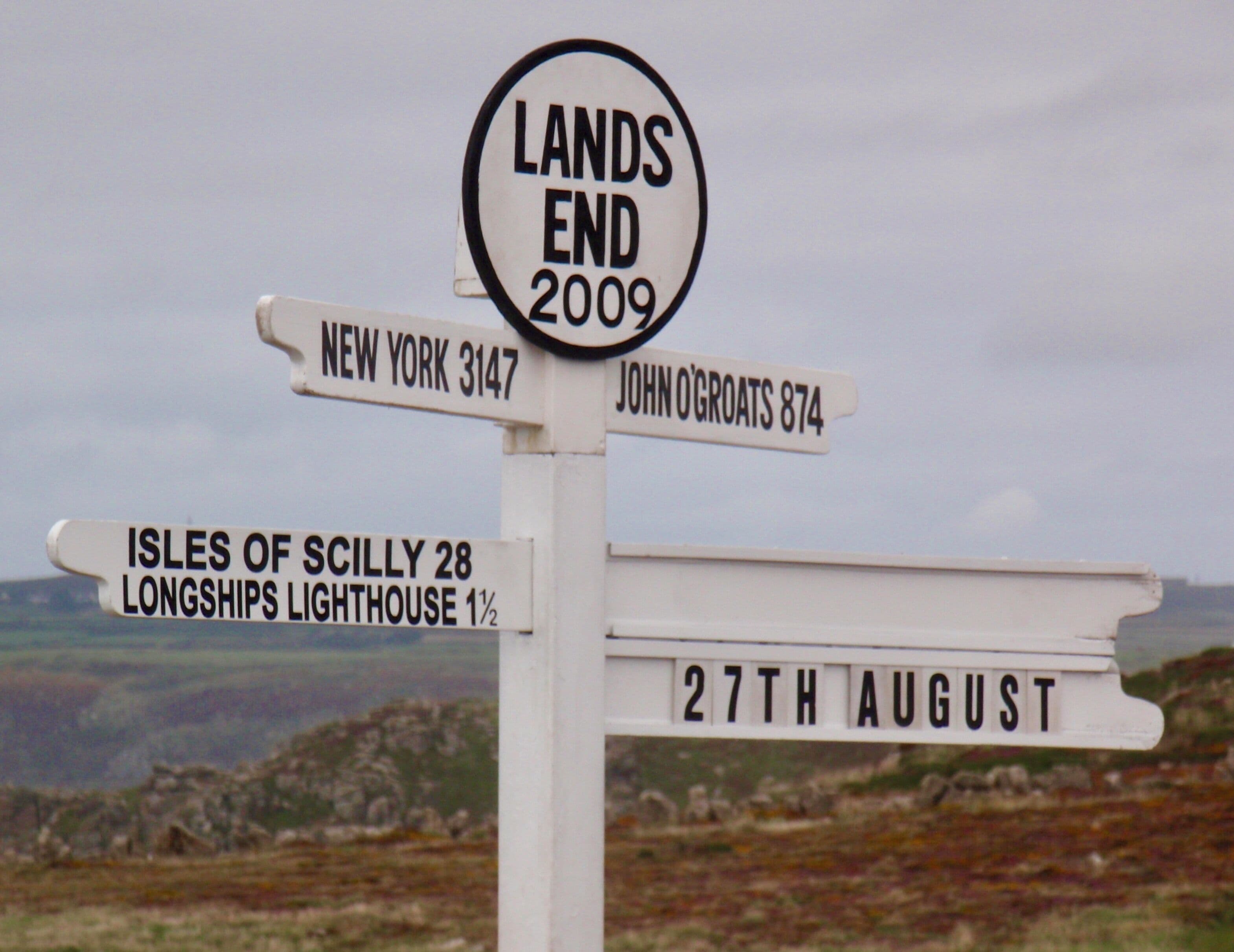 A directional signpost with destinations and dates.