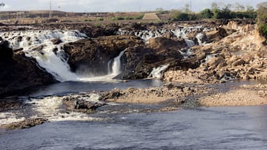 A waterfall cascading over rocky terrain with a bridge in the background.
