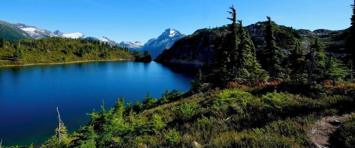 A lake surrounded by mountains and dense forest.