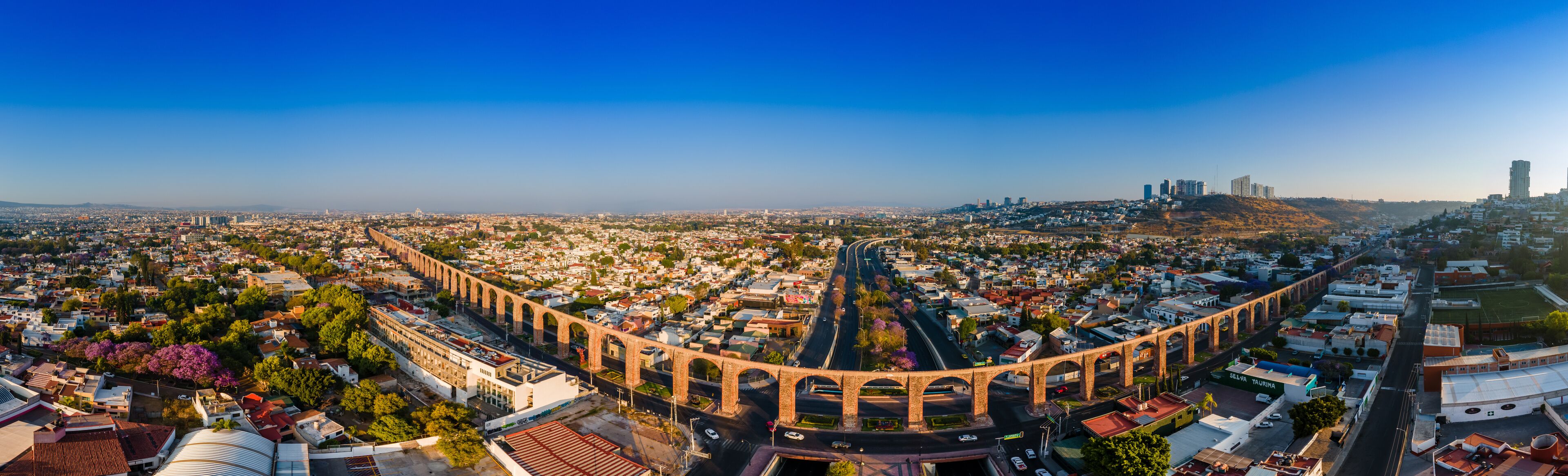 A cityscape with a prominent arched bridge, dense urban buildings, and distant high-rise buildings.