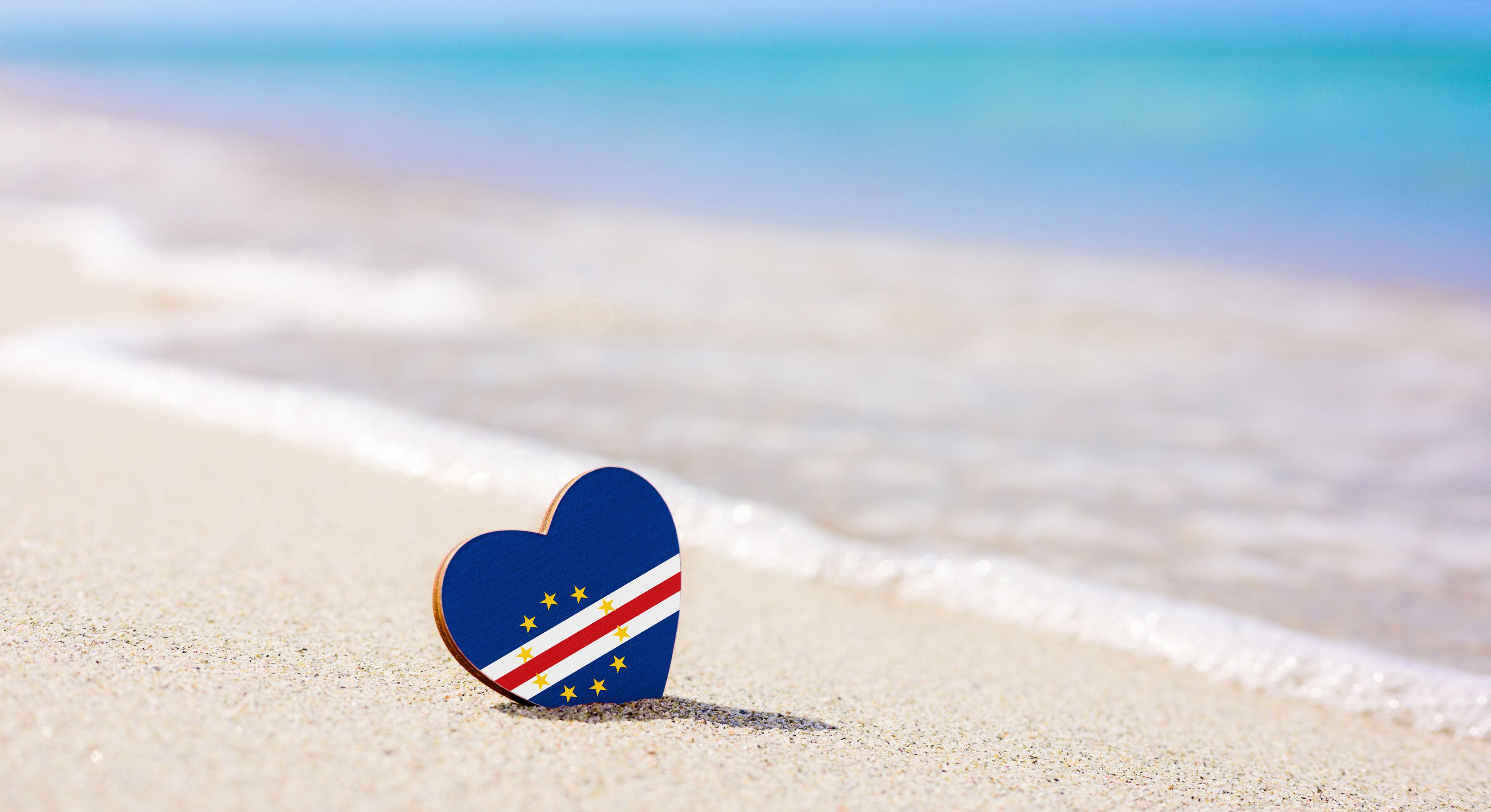 Flag of Cape Verde in the shape of a heart on a sandy beach. The concept of the best vacation in Cape Verde and Africa