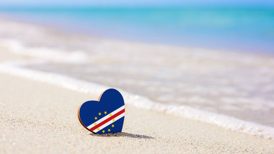 Flag of Cape Verde in the shape of a heart on a sandy beach. The concept of the best vacation in Cape Verde and Africa