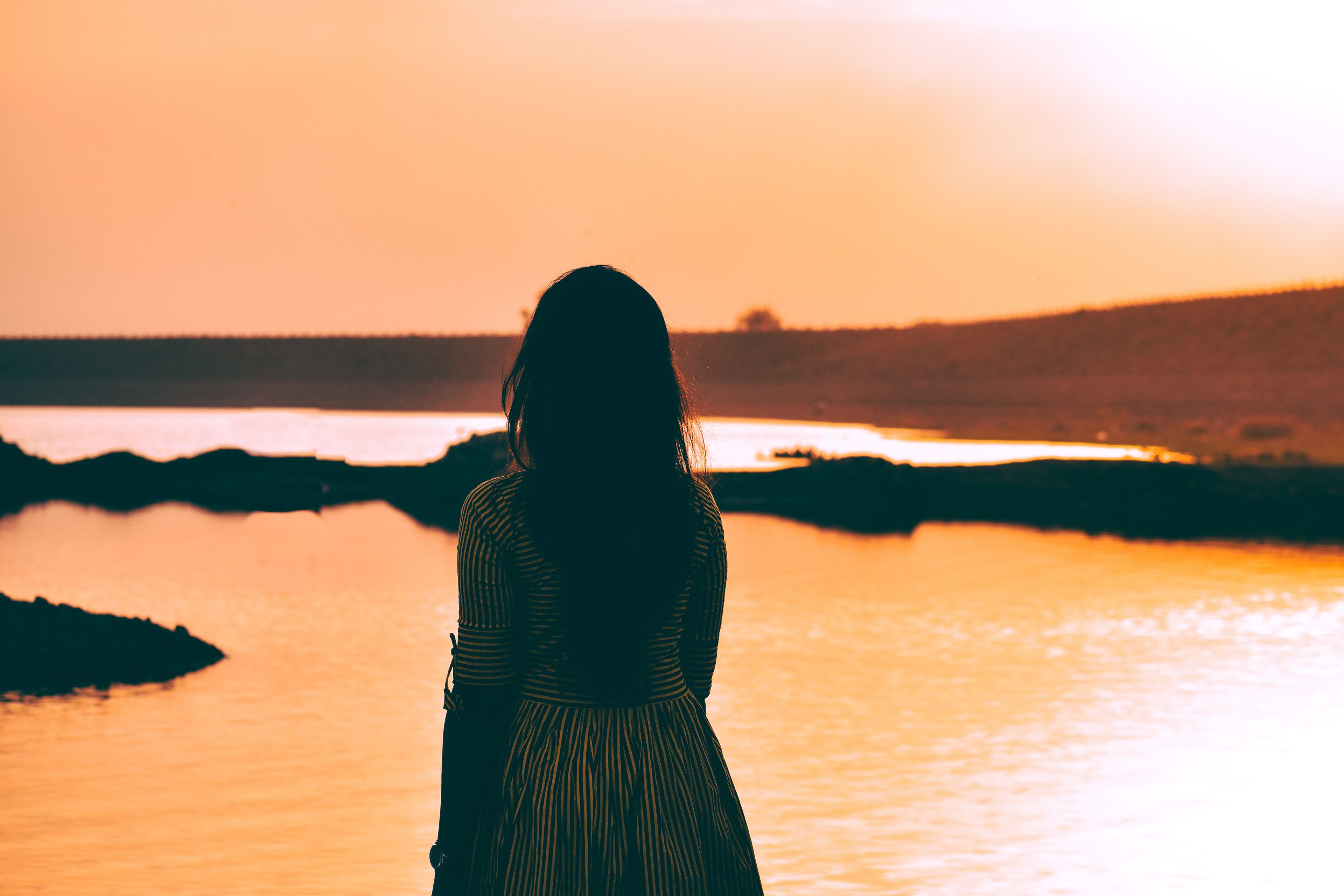 a beautiful girl standing in front of calm water and beautiful sunset sky at nyari dam, rajkot, India. 