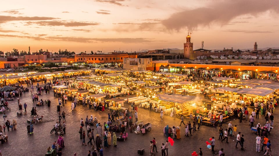 A bustling outdoor market with numerous stalls and people.