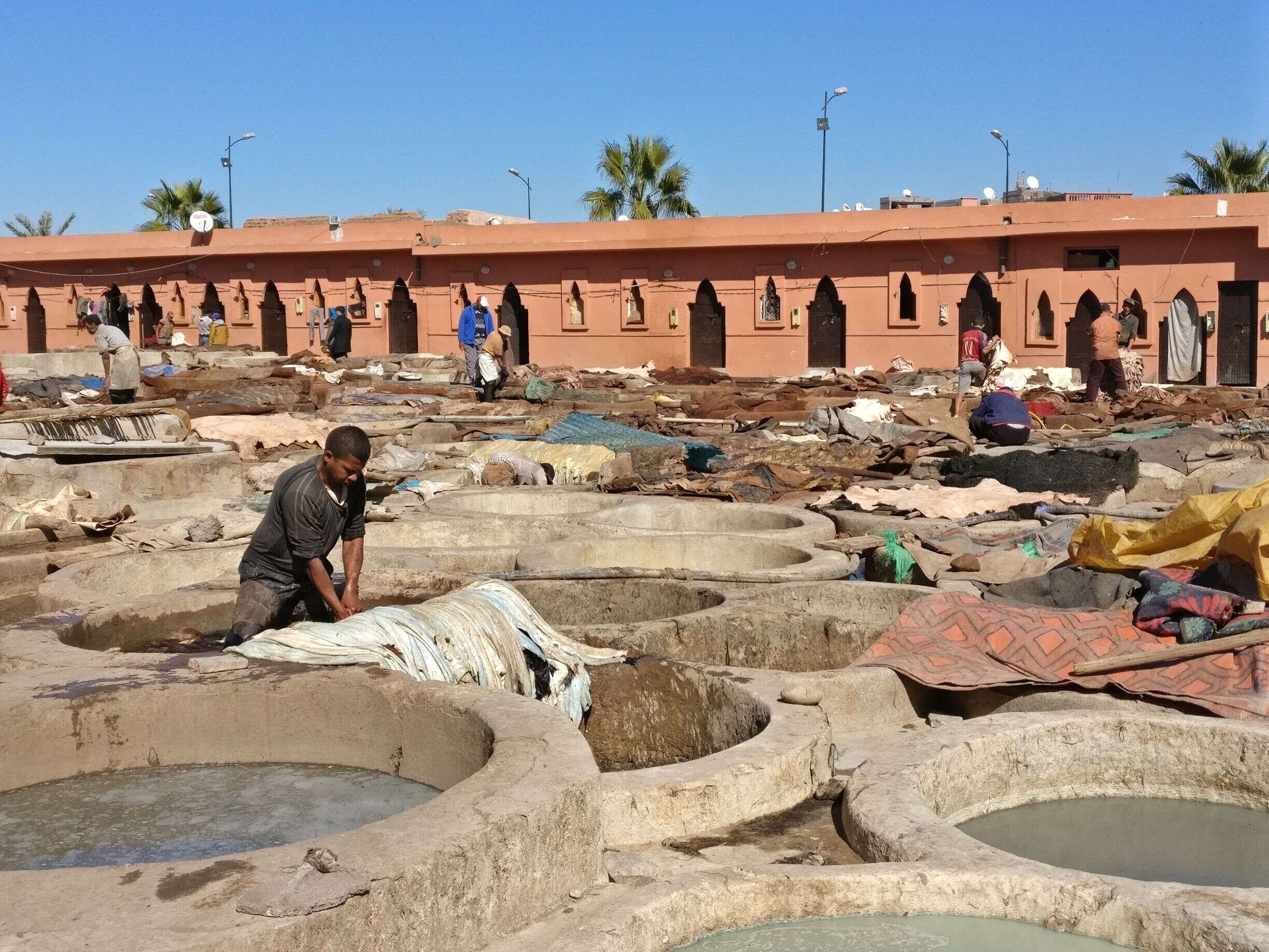 Zona de curtido con varios pozos y trabajadores procesando pieles.