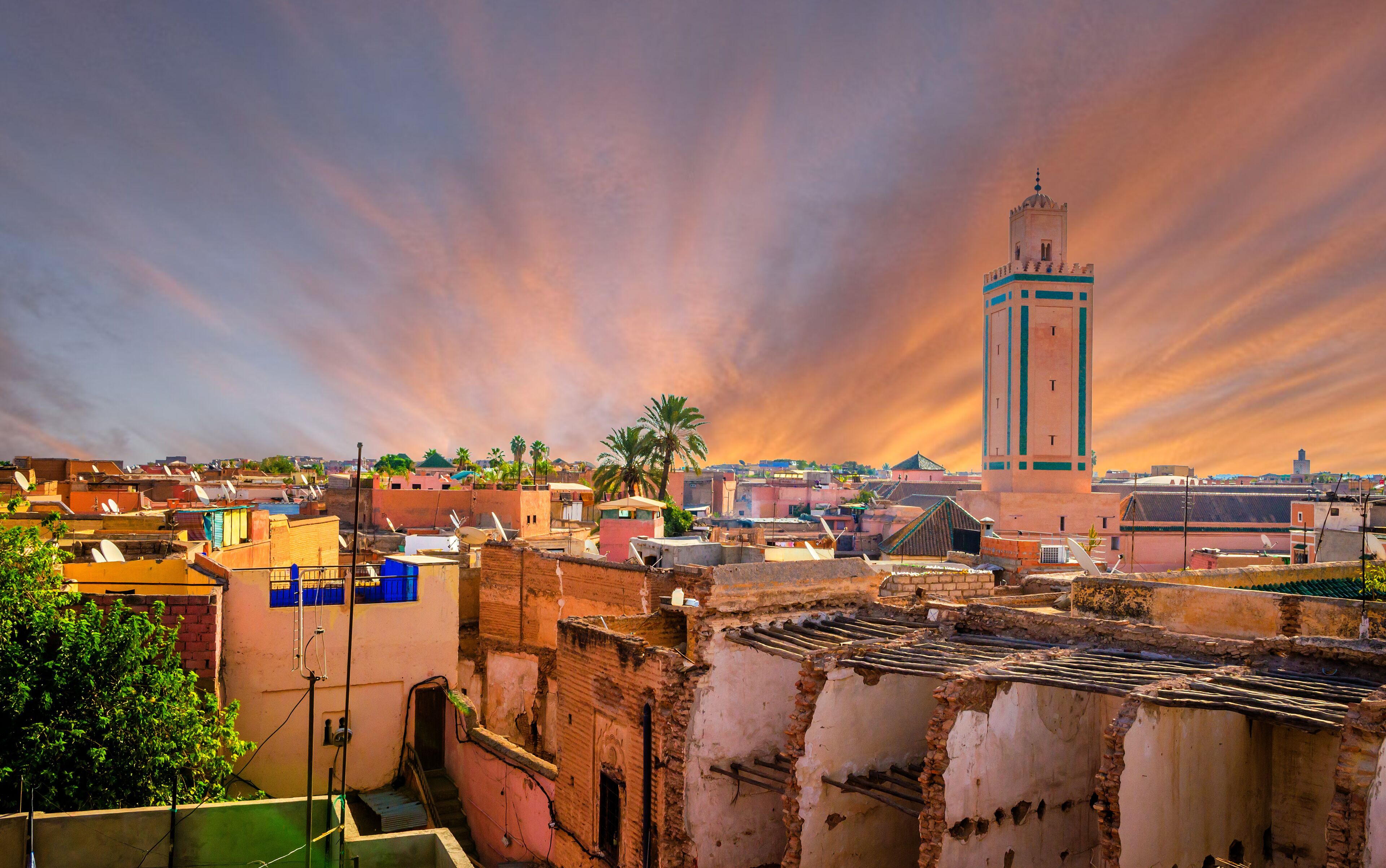 A cityscape with a prominent tower, traditional buildings, and a sunset sky.