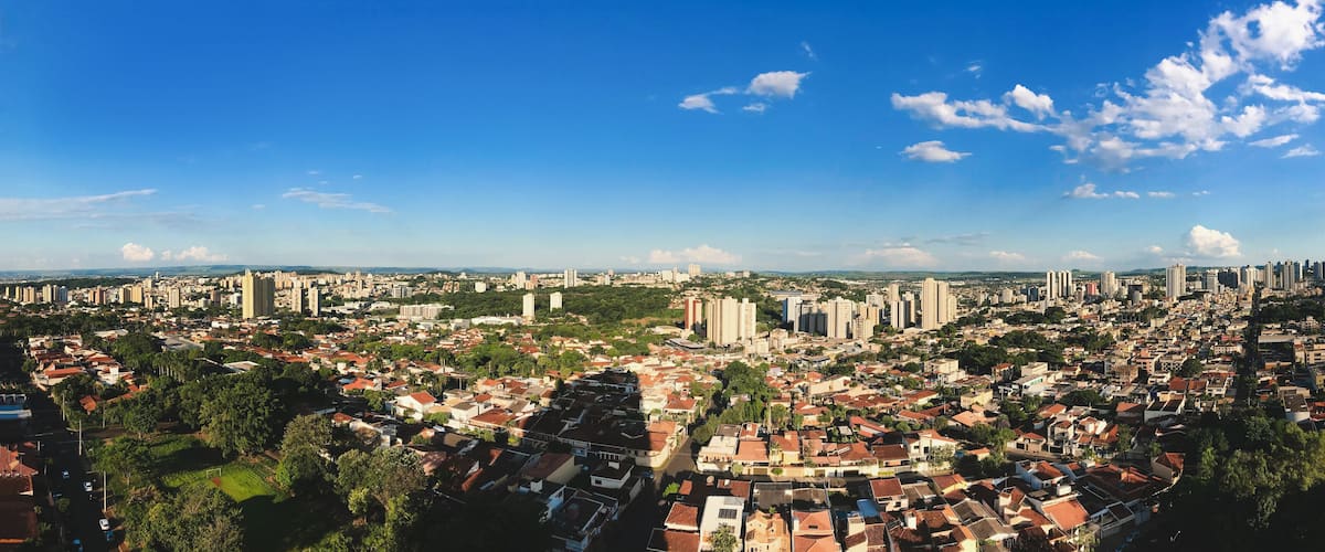 A panoramic view of a city with dense residential areas, numerous high-rise buildings, and a clear blue sky.