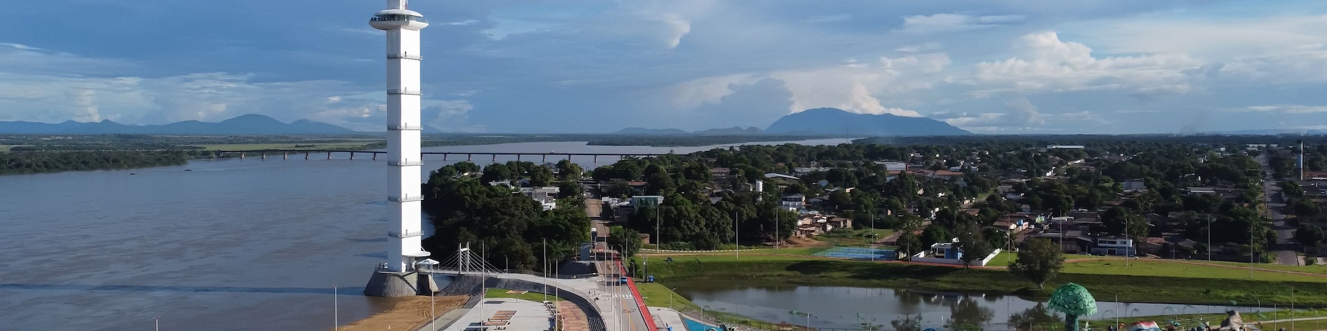 Un río, una torre blanca, un puente, un parque y un paisaje urbano.