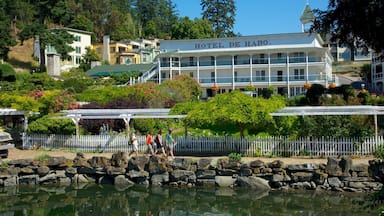 A waterfront view of Hotel de Haro with a stone wall and a reflection in the water.