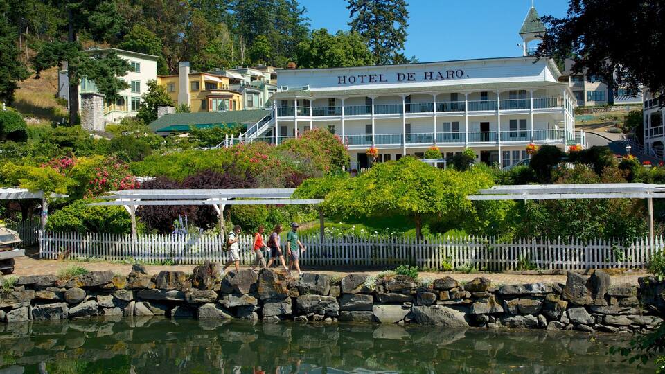 A waterfront view of Hotel de Haro with a stone wall and a reflection in the water.