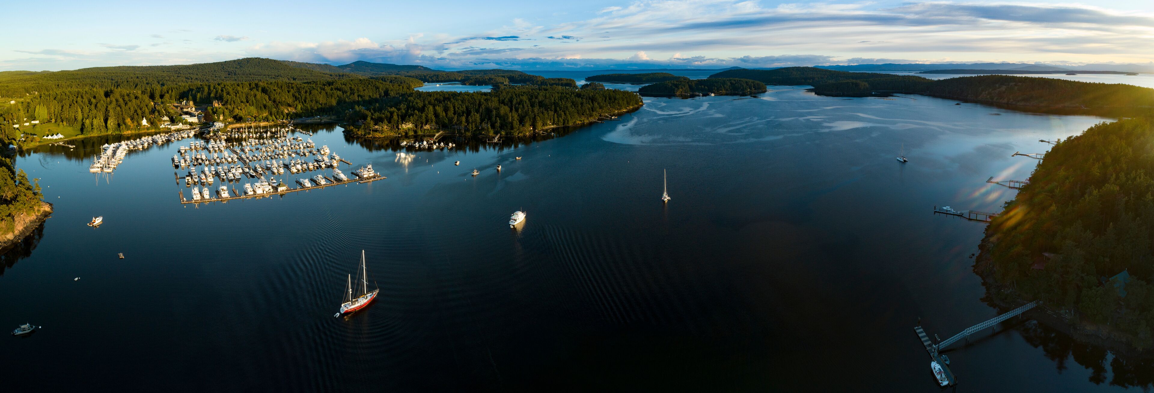 A marina surrounded by forested hills and a large body of water.