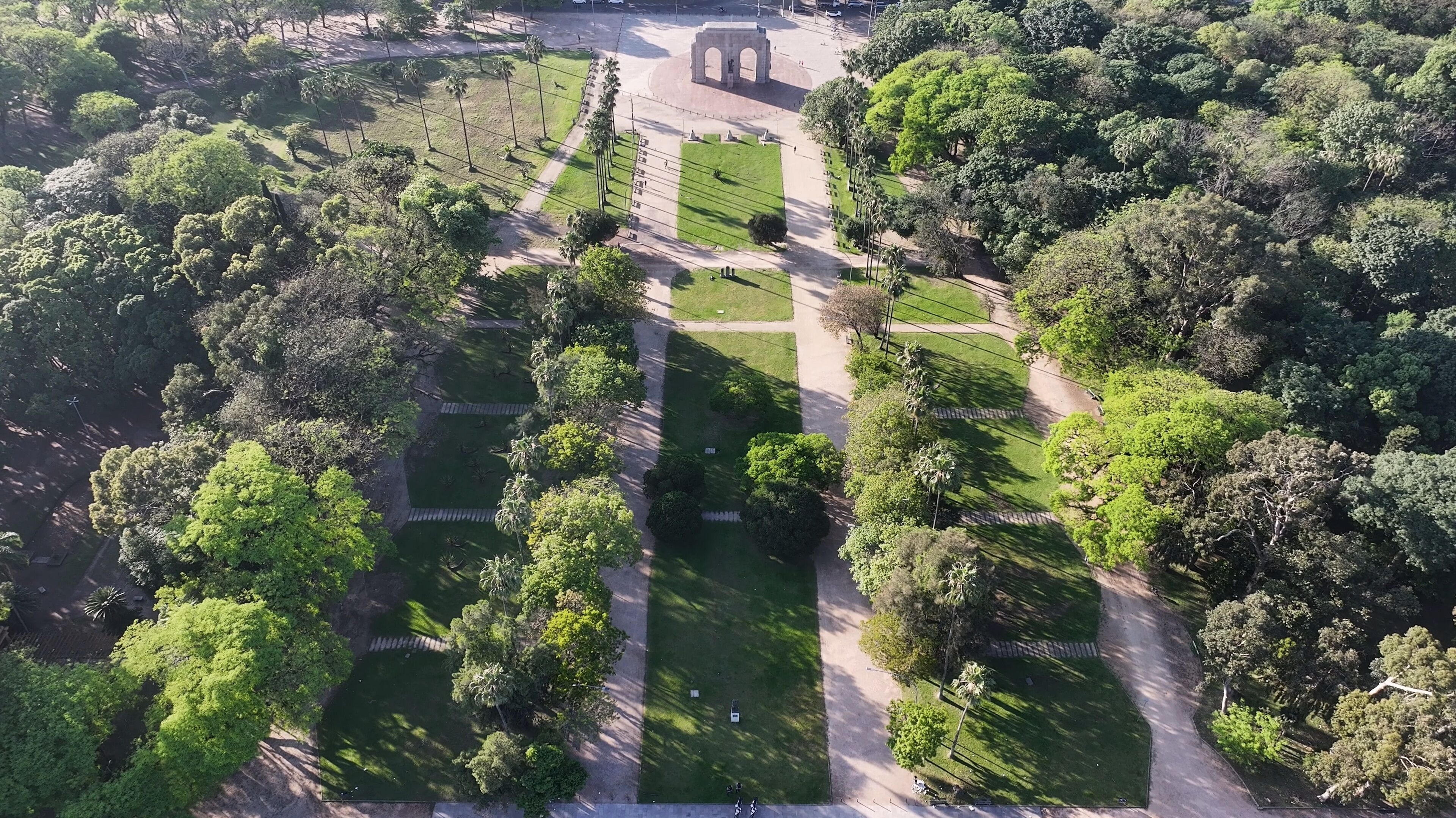 An aerial view of a park with a central monument, pathways, and lush greenery.