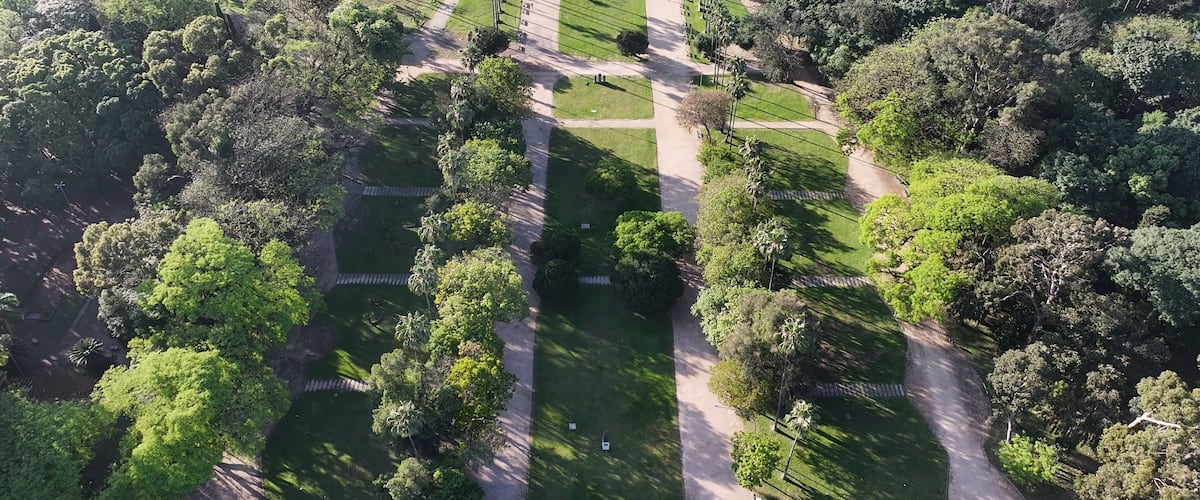 An aerial view of a park with a central monument, pathways, and lush greenery.