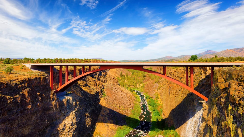 A red bridge over a canyon with a river below.