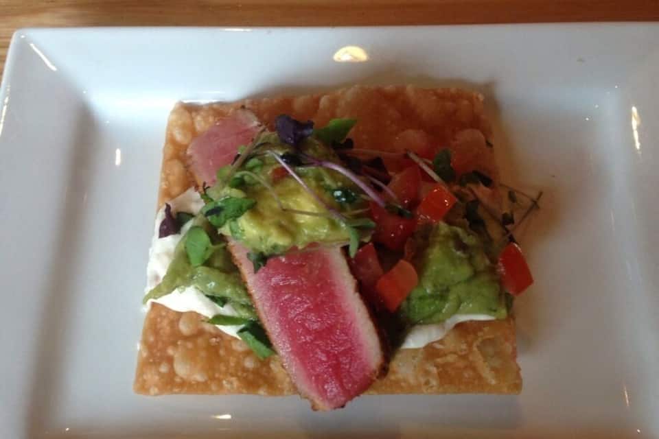 A square white plate with a food item on a wooden table.