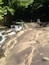 Een rotsachtig landschap met een kleine waterval en weelderige begroeiing.