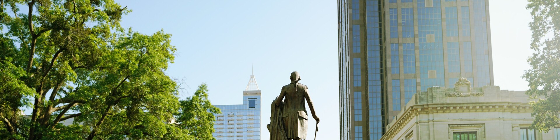 Uma estátua em um parque, com um prédio alto ao fundo.