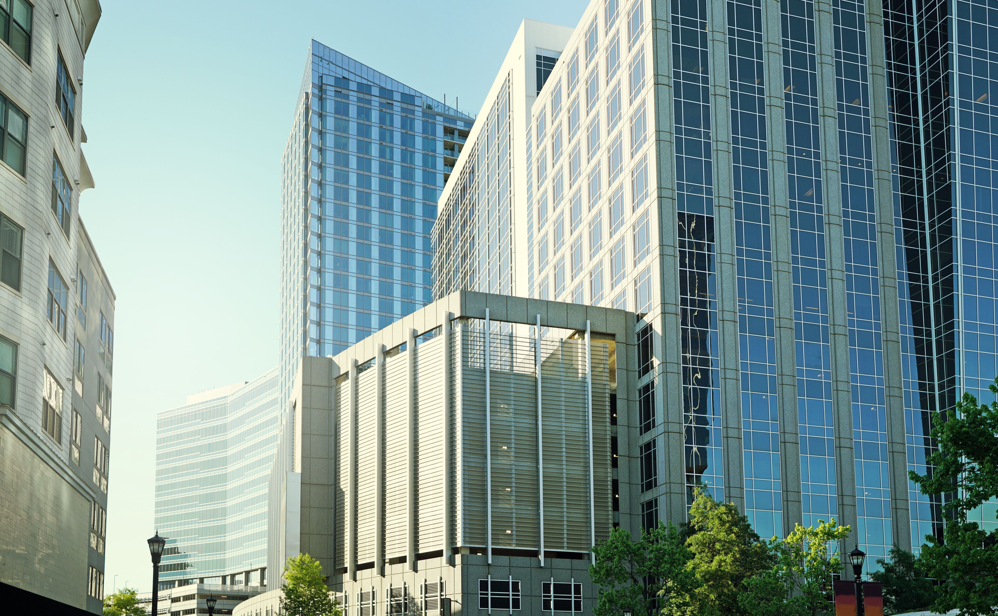 Paisagem urbana com edifícios altos modernos, uma estrutura de vidro curva e um lampião.