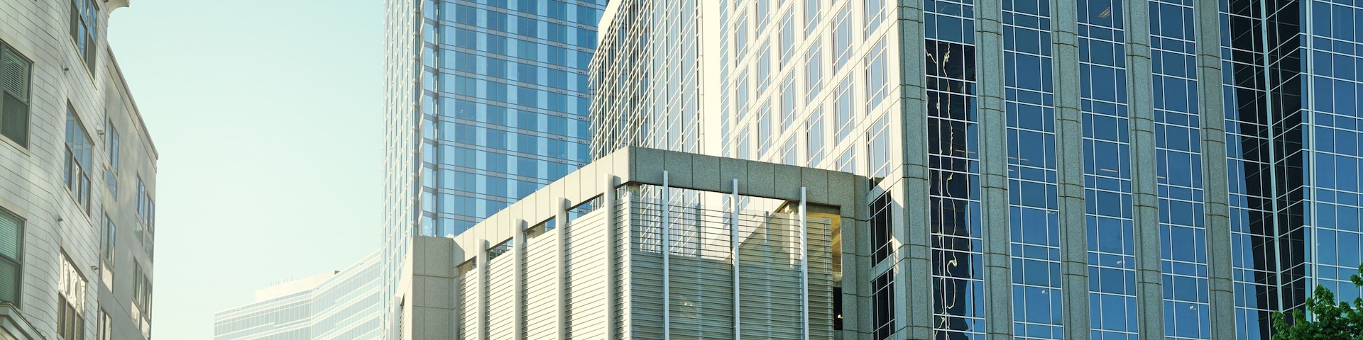 Paisagem urbana com edifícios altos modernos, uma estrutura de vidro curva e um lampião.