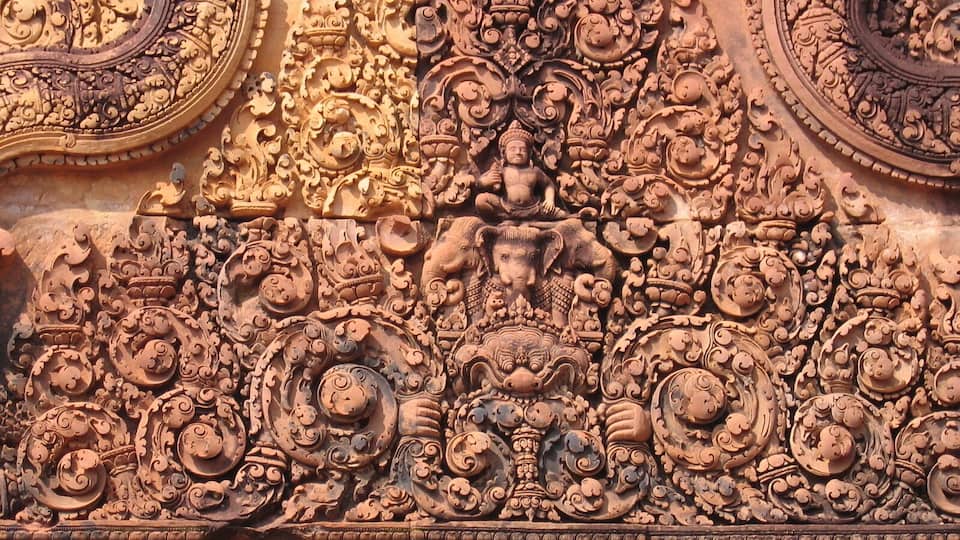 A detailed stone carving with intricate patterns and figures, including elephants and human figures.
