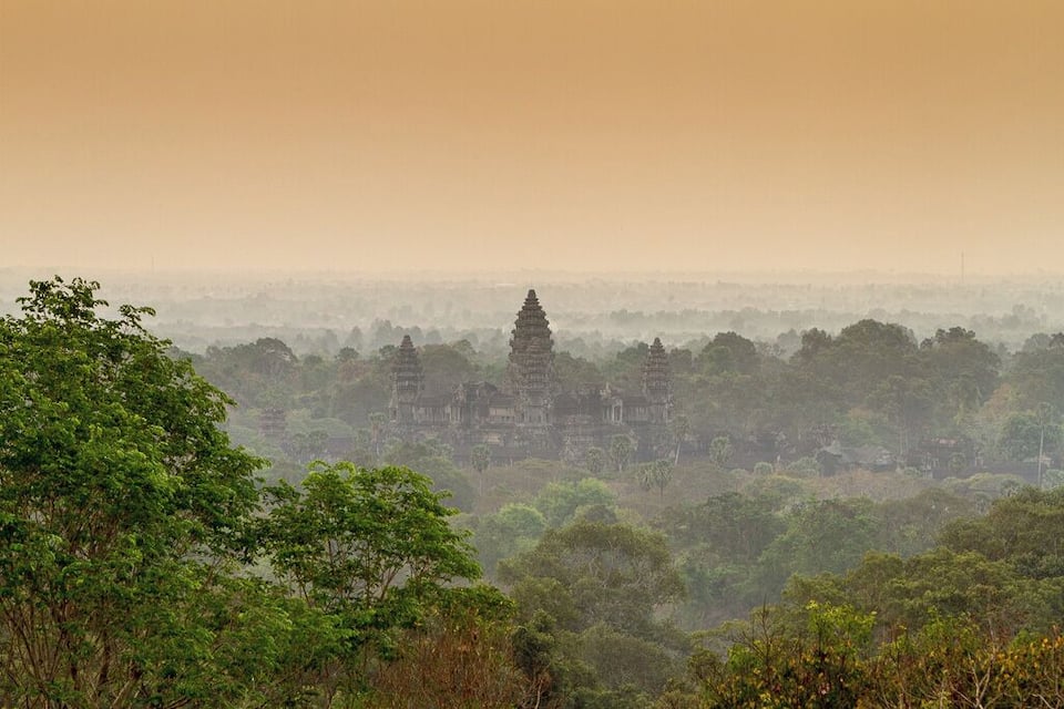 Une vue brumeuse du complexe du temple d’Angkor Vat, entouré d’une forêt dense.