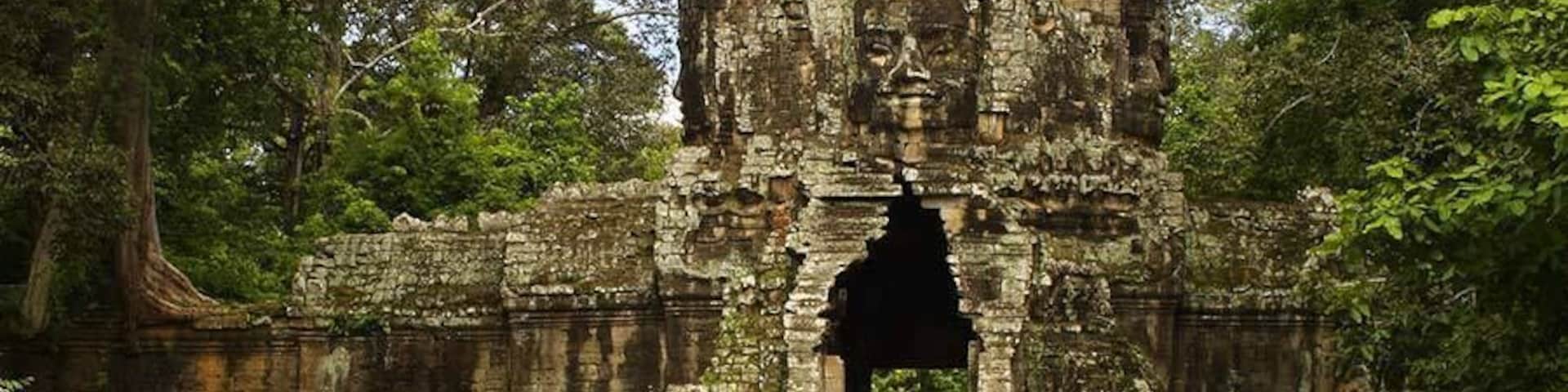 Entrada de um templo antigo de pedra, cercada por vegetação exuberante.