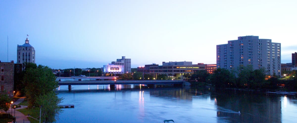 A river with boats docked, a bridge, and buildings in the background.