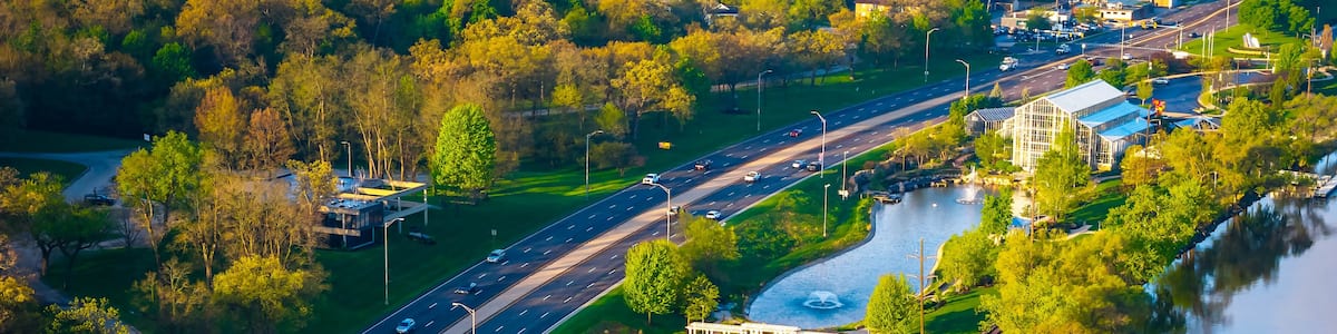 Eine Vogelperspektive eines Parks mit einem See, einer Straße und einer Brücke.