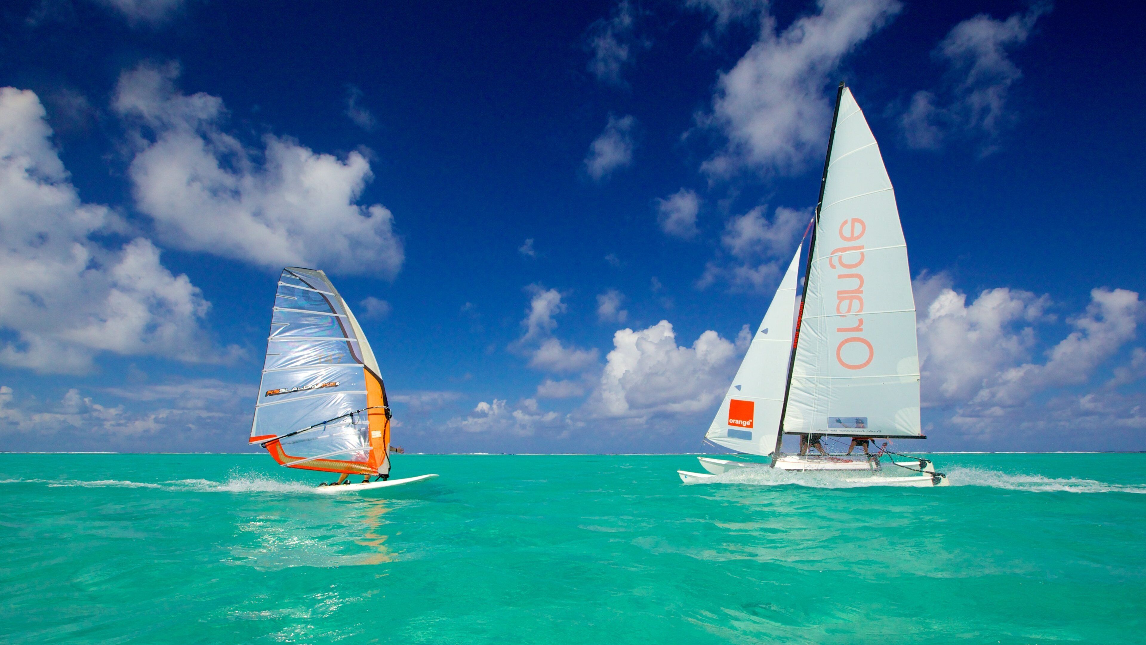 Two sailboats on turquoise waters with a clear sky.