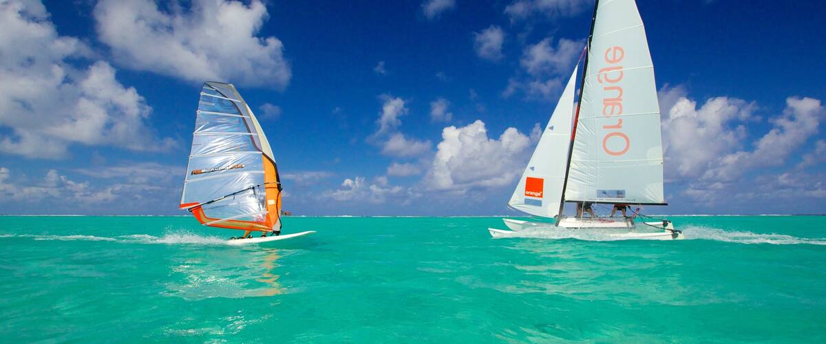 Two sailboats on turquoise waters with a clear sky.