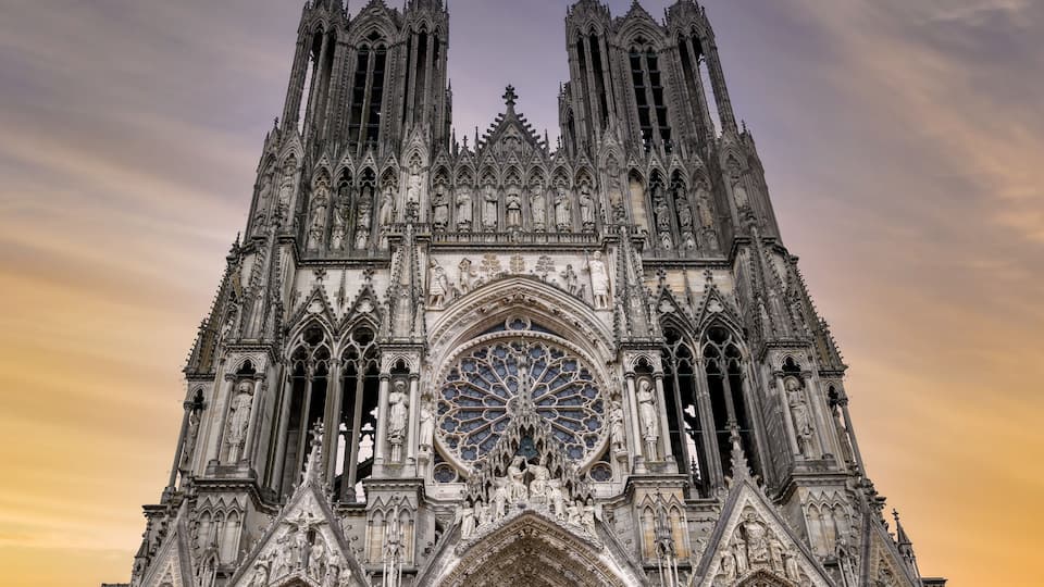 A Gothic cathedral with intricate stone carvings, a large rose window, and two tall spires.