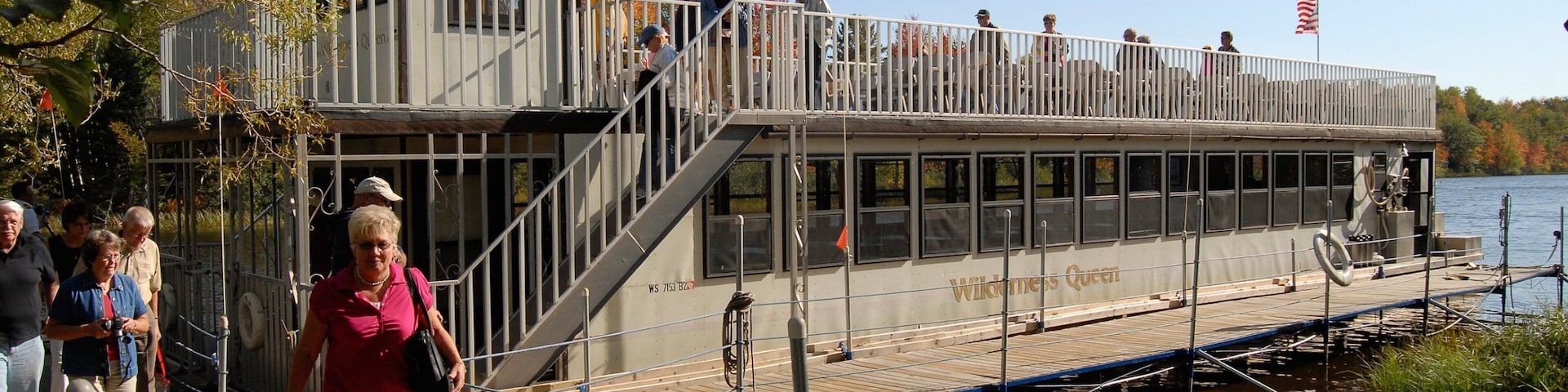 A riverboat docked at a pier with people boarding and disembarking.