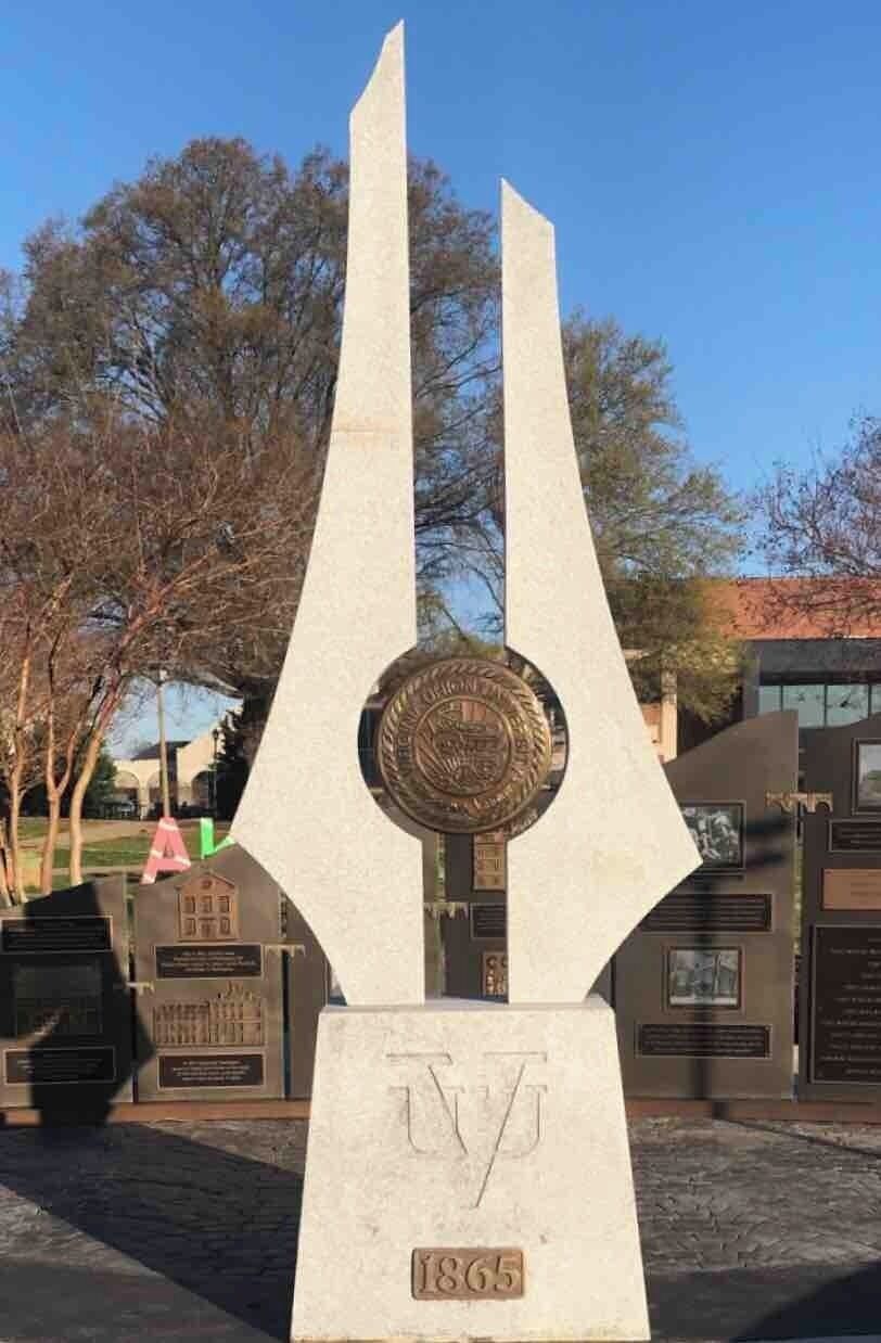 A monument with a triangular base and a circular emblem, marked with the year 1865.