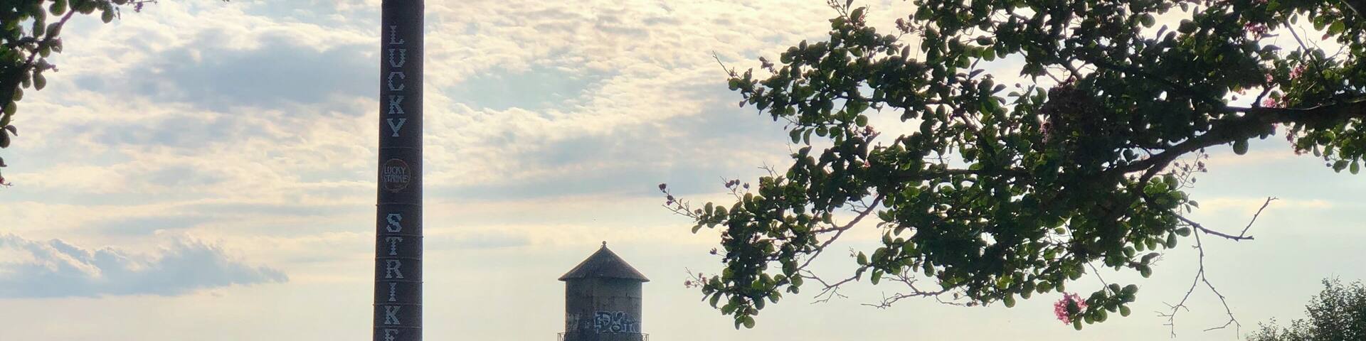 A water tower and a tall chimney with the word "LUCKY STRIKE" on a factory.