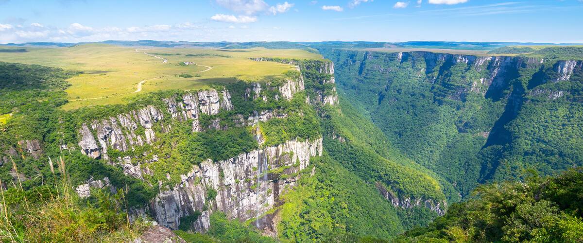 A vast canyon with steep cliffs and lush greenery.