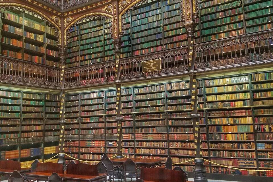 Een statige bibliotheek met versierde architectuur, rijen boekenplanken en antieke houten tafels.