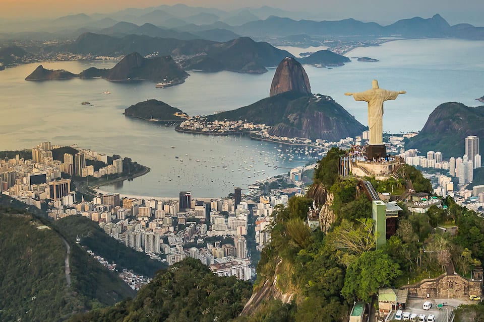 Christ the Redeemer statue overlooking Rio de Janeiro, with the cityscape and Guanabara Bay in the background.