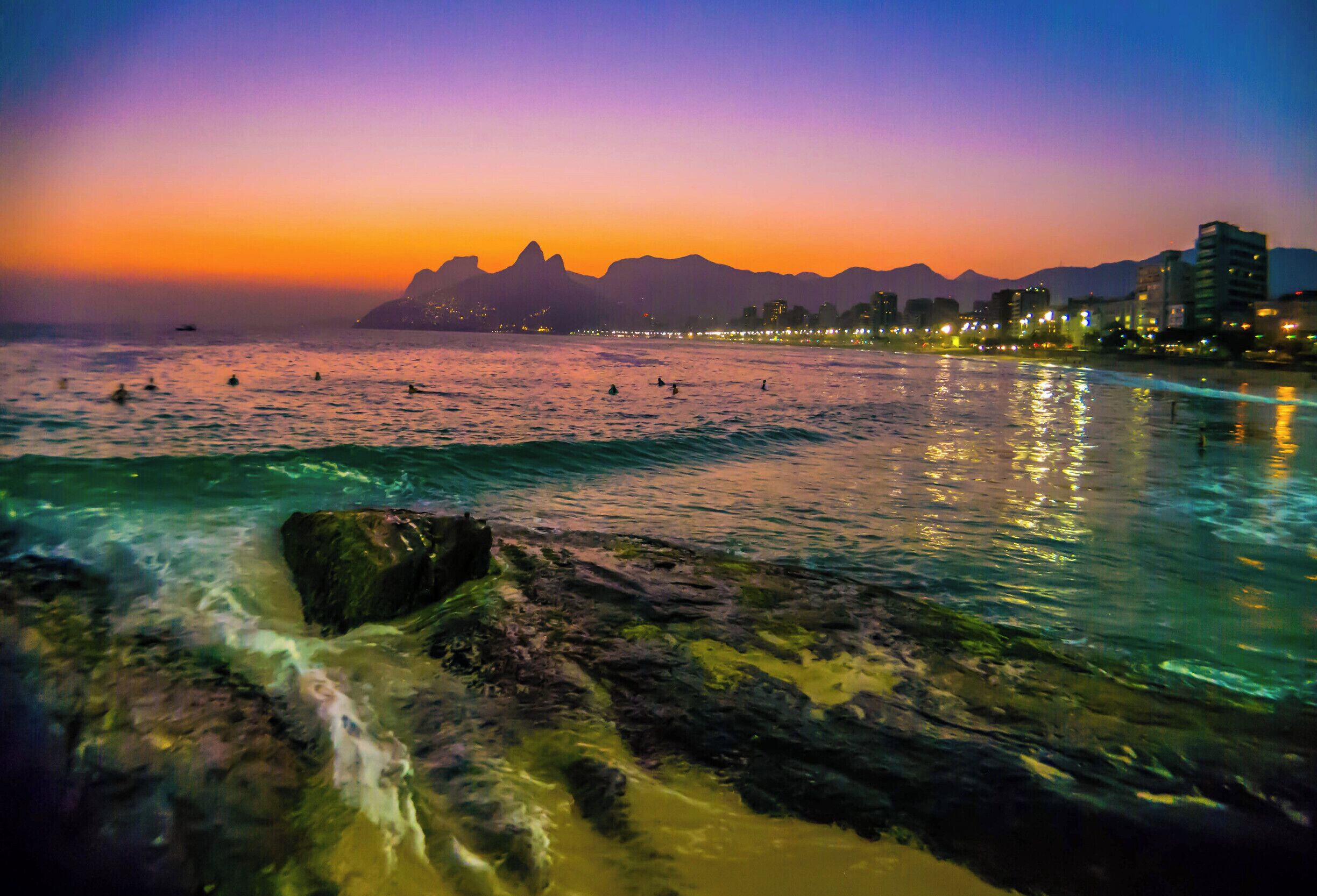By far the best spot to watch the sunset at the beach (Sugarloaf mountain is THE best in Rio).  

New York Times: “If you want to know why people come to Rio de Janeiro, and came even during its years of bloody, decadent decline, stand on the Arpoador Beach promenade at day’s end. Before you lies an orchestral finale of a sunset: iridescent water, pastel-streaked skies and hazy silhouettes of cliffs to the west. Behind you are swarms of Cariocas, as Rio natives are known: men with phones tucked into the fronts of their bathing suits, swimmers shaking off droplets of water before ordering caipirinhas at an outdoor bar. At the moment when the neon-pink sun slips below the horizon, everyone stops, stands and claps: a nightly salute to city, beach and sky.”