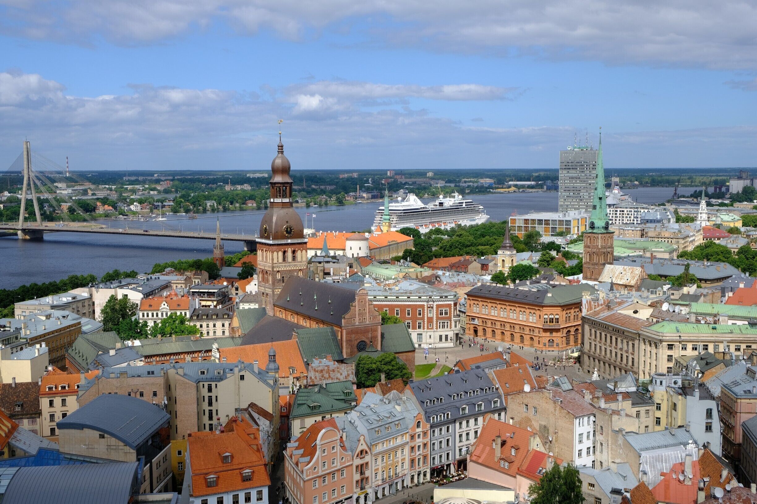 A cityscape with historic buildings, a river, a bridge, and a cruise ship.