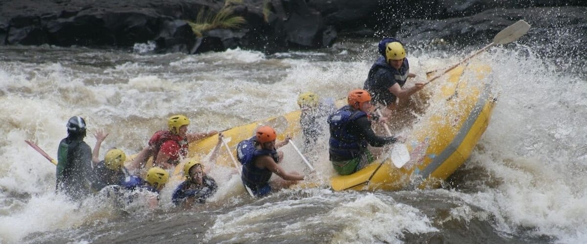 A group of people in a yellow raft navigating turbulent waters.