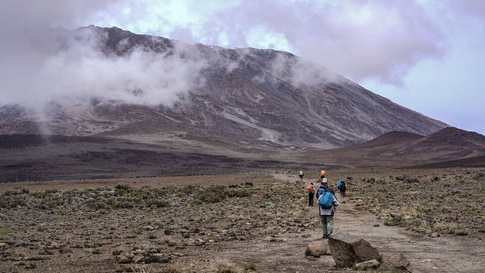 A rugged mountainous landscape with hikers on a rocky trail.