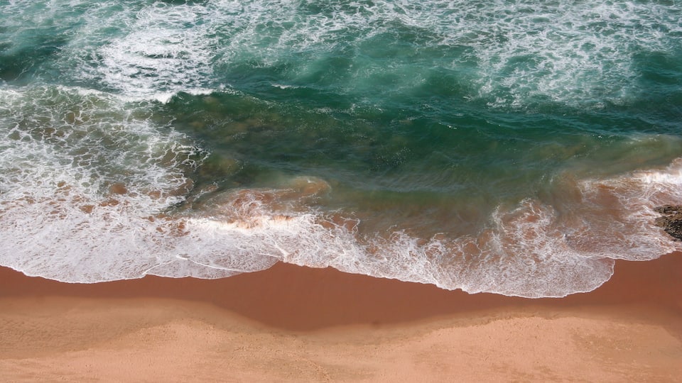 A sandy beach with waves crashing onto the shore.