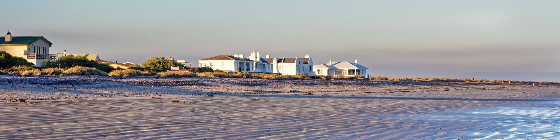 Homes next to a wide empty beach at low tide in the early morning on the West Coast near Dwarskersbos in the Western Cape, South Africa